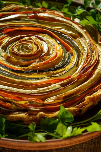 Vegetable pie Mexican sun. Round open pie made from zucchini, eggplant and carrots. Close-up top view. Healthy vegetable food. Vegetarianism. Spiral tart with eggplants.