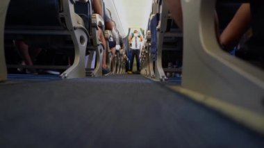 Ukrayna, Odesa - 3 Ağustos 2021: Uçaktaki bir hostes bir koltuğa nasıl emniyet kemeri takılacağını gösteriyor. Koltuklar arasındaki koridordaki uçuş görevlisi uçuş güvenliğini göstermektedir. UIA Yolcuları.