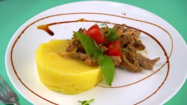 Fransız Buf Strogano ile sığır stroganoff ince dilimlenmiş krema soslu sığır eti. Patates püresi, domates ve fesleğenli dana eti. Dönen beyaz bir tabakta et yemeği. Yürekli yemek