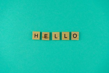 Merhaba de. Sözcük ahşap harflerle yazılmıştır. Üst Manzara. Motivasyon. Mavi arka plan. Boşluğu kopyala.