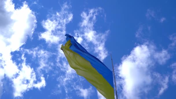 La bandera amarillo-azul de Ucrania ondea contra el cielo azul. Símbolo ucraniano. Una gran bandera en un asta de la bandera ondea en el viento. — Vídeos de Stock