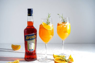 İtalyan tentürü Aperol, Aperol Spitz kokteyli yapmak için. Şişede kırmızı-turuncu şarap. Alkolik içki. Portakallı ve otlu aperatif. Yiyecekler beyazda hala hayat. Ukrayna, Kyiv - 26 Ağustos 2021