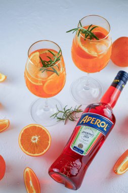 İtalyan tentürü Aperol, Aperol Spitz kokteyli yapmak için. Şişede kırmızı-turuncu şarap. Alkolik içki. Portakallı ve otlu aperatif. Yiyecekler beyazda hala hayat. Ukrayna, Kyiv - 26 Ağustos 2021