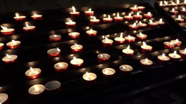 Kilisede yanan adak mumları. Mumlar yanıyor. Karanlıkta mum ışığı.