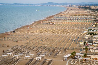 Güneş pansiyonları ve şemsiyeleri olan geniş kumsallı bir tatil köyü. Rimini İtalya 'da yaz mevsimi.