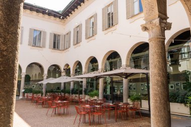 İtalya, Milano - 17 Temmuz 2025 Sokak Kafesi. Milano 'nun merkezindeki eski ev cephesi. Piccolo Tiyatrosu giriş antikacı kemeri. İtalya mimari binası