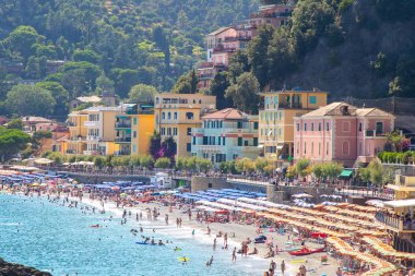 Monterosso 'daki çok renkli evler. Yazın sahilde şemsiyeler. Ligurian Denizi kıyısında İtalyan bayramı. Liguria köyü. İnsanlar turist. İtalya, Monterosso - 15 Temmuz 2025.