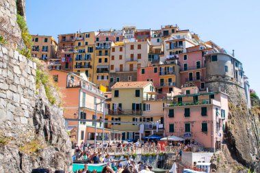 Bir sürü turist. Uçurumdaki parlak renkli evler. Manarola İtalyan köyü Liguria denizi. Cinque Terre 'de. İtalya, Manarola - 15 Temmuz 2025.