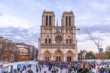 Paris, Fransa - 30 Ekim 2025: Sonbahar akşamı gökyüzünde Notre Dame de Paris. Sokaktaki birçok insan turizm yüzünden. Eski Fransız mimarisi