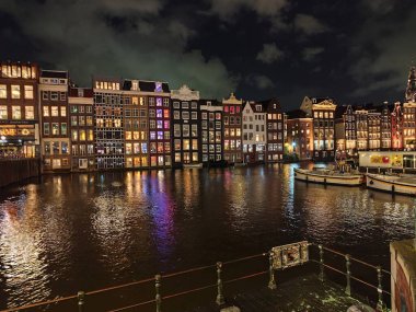 Amsterdam Hollanda - 27 Ekim 2025: Amsterdam gece kenti kanal suyu yakınlarındaki renkli evler. Sokak mimarisi. Tarihi Merkezde Eski Bina Gezisi.