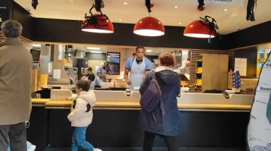 Fransa, Paris - 29 Ekim 2025: McDonalds Kafe İçi. Fast food restoranı. Kasadaki kasiyer müşteriyi kabul eder ve sipariş verir. Sıraya girin