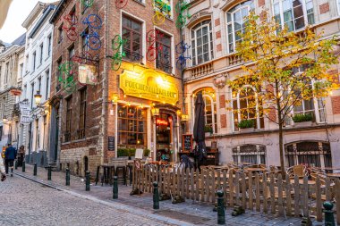 Brüksel, Belçika - 28 Ekim 2025: Brüksel sokaklarındaki Poechenellekelder barı. Eski bir kafeterya. Bistro sokak yemekleri masası.