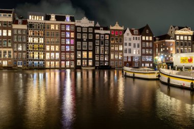 Amsterdam Hollanda 'da Renkli Row Evleri Kanal Caddesi boyunca uzanan gece kanalı mimarisi - 28 Ekim 2025