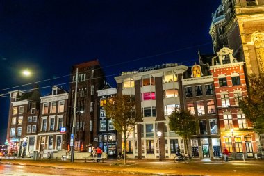 Amsterdam Hollanda, gece caddesinde. Renkli evler ve kanal suyu. Pencerelerinde lambalar ve fenerler olan Akşam Gezisi sokak mimarisi. Eski bina. Amsterdam Hollanda - 28 Ekim 2025