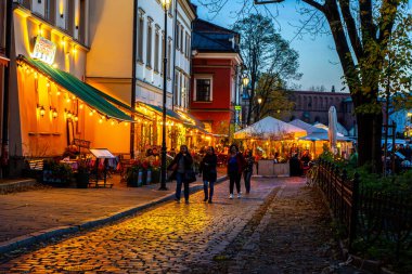 Akşam kasabasında insanlar yürür. Krakow 'daki Yahudi Mahallesi' ndeki kafe restoranı. Geceleri sokak serserisi. Krakow, Polonya - 1 Kasım 2025