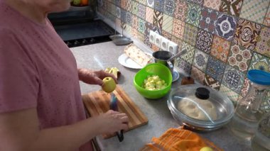 Elmalı turta yap. Mutfakta yemek pişiren yaşlı bir kadın. Elmaları bıçakla kesmek. Yemek pişir