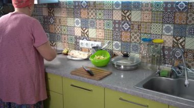 Elmalı turta yap. Bir rulo için ince pita ekmeği. Mutfakta yemek pişiren yaşlı bir kadın. Yemek pişir