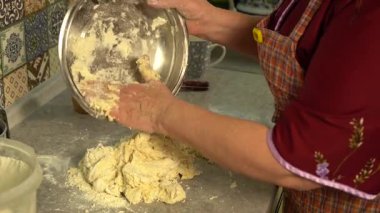 Kadın, elleri masanın üzerinde bir kasede hamur yoğuruyor. Evde yemek pişirmek..