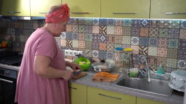 Mutfakta yemek pişiren yaşlı bir kadın. Elmaları bıçakla kesen eller. Evde yemek pişir.