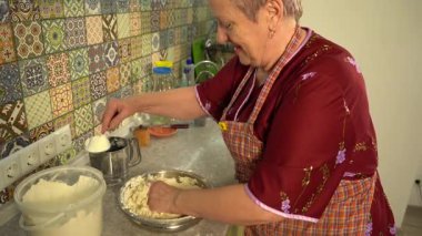 Unu süzgeçten geçirin. Kıdemli kadın hamur yoğurur, elleri masanın üstünde. Evde yemek pişirmek..