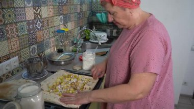 Kadın evde yemek pişiriyor. Elmaları pide ekmeğine sar. Pişirme tepsisinde yuvarlan.