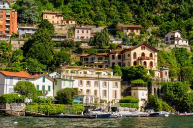 Dağdaki Como İtalya Gölü 'nde çok renkli evler mimari inşa ediyor. Sudaki tekne.