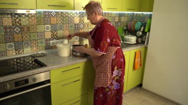 Yaşlı kadın evde yemek pişiriyor. Hamur için un dök..