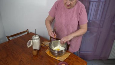 Kadın kırıyor ve süzme peynire yumurta ekliyor. Bir büyükanne güveç ve peynirli kek hazırlar..