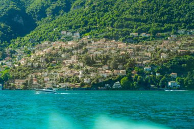 Dağdaki Como İtalya Gölü 'nde çok renkli evler mimari inşa ediyor. Suyun üstünde bir tekne. Yeşil doğa
