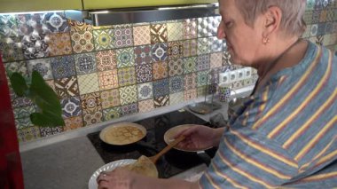 Son sınıf öğrencisi, kızartma tavasında ince krepler pişiriyor. Gel-git krep günü. Büyükannem mutfakta yemek pişirir..