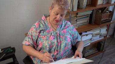 Yaşlı bir kadın oturur ve bir skeç çizer. Son sınıf öğrencisi. Büyükanne hobisi