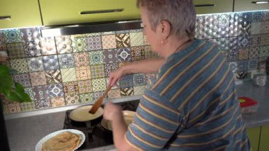 Kızartma tavasında ince krep kızartan yaşlı kadın. Gel-git krep günü. Büyükannem mutfakta yemek pişiriyor. Evde fırın