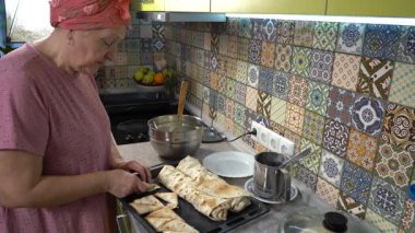 Evde yemek pişiren yaşlı bir kadın. Peynirli turta yap. Büyükanne.