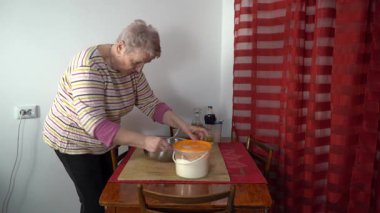 Yaşlı kadın hamur yoğuruyor. Un masanın üstünde. Evde yemek pişirmek.