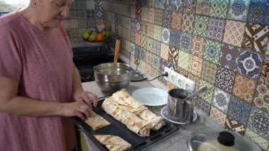 Evde yemek pişiren yaşlı bir kadın. Süzme peynirli turta yap. Büyükanne.