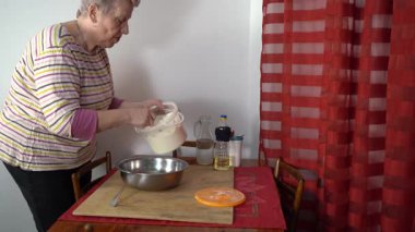Yaşlı bir kadın bir kaseye un döküyor..