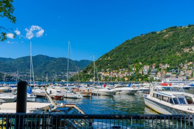 Como Gölü rıhtımında yaz günü tekneler. İtalyanların seyahat ettiği çok renkli evler. İtalya, Como - 17 Temmuz 2025.