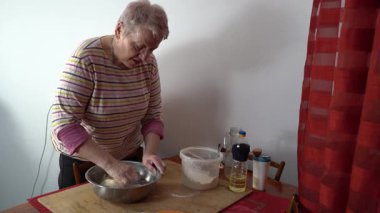 Masada hamur yoğuran kıdemli bir kadın. Evde yemek pişirmek ve konuşmak..