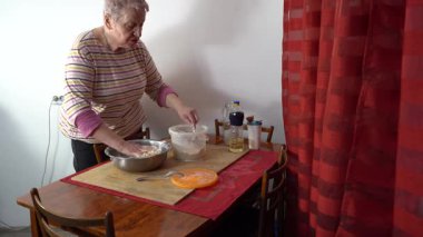 Masada hamur yoğuran yaşlı bir kadın. Evde yemek pişirip konuşmak. Un içinde eller.