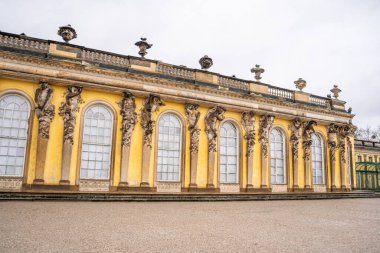 Potsdam, Almanya 'da Kral 2. Frederick' in Sanssouci Sarayı 'nın çatısını destekleyen süvariler ve Atlantisliler. Rococo tarzında eski bir mimari. Sarı cephe duvarı ve pencereleri.
