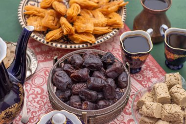 Kurumuş hurma ve helva. Tatlı meyve yemeği. Kahve fincanlı tatlı. Randevu kasesi masada..