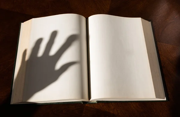 Un libro abierto y sombra de mano — Foto de Stock