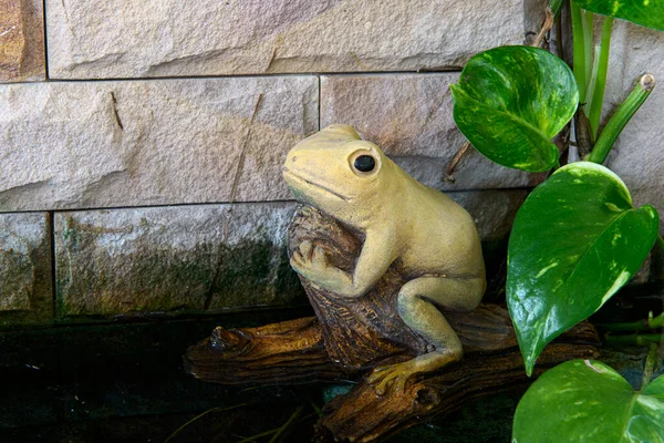 黄色的青蛙雕像坐落在古老的木头上装饰花园 — 图库照片