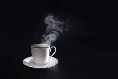 Siyah arka planda izole edilmiş beyaz bardakta dumanlı sıcak kahve