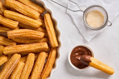 Hafif arka planda şekerli ve çikolatalı Churros. Geleneksel İspanyol fast food. Ev yapımı pişirme. Üst görünüm.