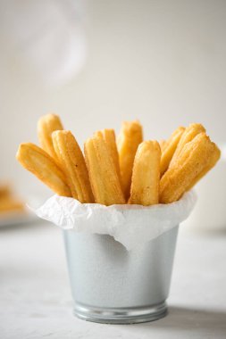 Hafif arka planda şekerli ve tarçınlı Churros. Geleneksel İspanyol sokak fast food. Ev yapımı pişirme..