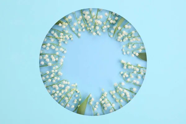Komposition mit weißen Blüten. Zusammensetzung der Maiglöckchen in einem Kreis auf hellblauem Hintergrund. — Stockfoto