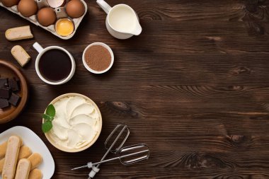 Tiramisu tatlısını hazırlamak için. Ahşap kahverengi tahtadaki malzemelerin üst görüntüsü. Bir yazı için boş alan.