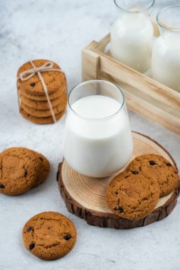 Tahta bir masanın üzerinde çikolatalı kurabiyelerle dolu cam bir bardak.