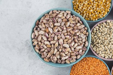 Bir sürü pişmemiş fasulye, mısır ve mermer yüzeyde kırmızı mercimek.